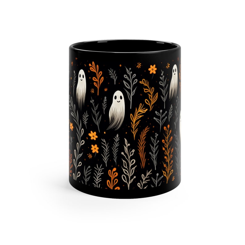 Black ceramic coffee mug featuring a whimsical Halloween design with cute white ghosts surrounded by orange, yellow, and gray autumn foliage and flowers on a dark background. The mug has a glossy finish and a large handle for comfortable use. Available in 11 oz or 15 oz sizes, this festive fall mug is both microwave safe and dishwasher safe, making it a practical yet fun seasonal drinkware choice for coffee, tea, or hot cocoa. (11 oz shown)