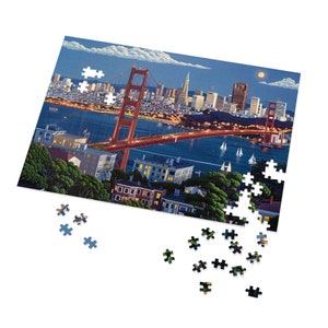 May include: A jigsaw puzzle featuring a nighttime view of the Golden Gate Bridge in San Francisco. The bridge is lit up in red and orange, and the city skyline is visible in the background. The puzzle is partially assembled, with some pieces missing.