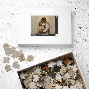 May include: A 520 piece jigsaw puzzle featuring a painting of the Holy Family. The image shows Mary, Joseph, and baby Jesus in a warm, golden light. The puzzle box is white with a black border and the words "Custom Made" and "520 Piece Puzzle".