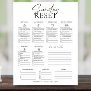 Peut inclure: Une liste de contrôle Sunday Reset blanche imprimée avec du texte et des icônes noirs. Elle comprend des sections pour la cuisine, les salles de bain, les chambres, les salons, la lessive, la planification, les soins personnels et des notes, avec le logo Pip & Bubs.