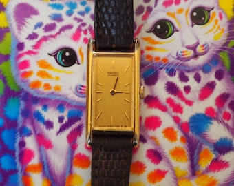 Reloj Seiko Tank de cuarzo vintage de 1983, modelo 2E20-6120, rectangular, tono dorado, con correa de piel de lagarto marrón.