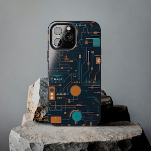 May include: A black phone case with a circuit board design. The case has orange and blue accents. The phone case is on a grey rock surface.