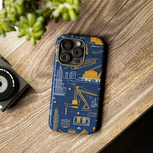 May include: A blue phone case featuring a pattern of yellow construction equipment, such as cranes, lorries, and buildings. The case has a cut-out for the camera lens.
