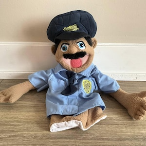 Puede incluir: Una taza de cerámica blanca con un asa negra y el texto "But First, Coffee" en negrita negra. La taza se encuentra sobre un fondo borroso, sugiriendo un ambiente acogedor.