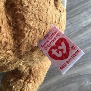 May include: A brown plush toy with a pink Ty tag that reads "The Beanie Babies Collection &copy; Ty Inc.  Small Only/Petite"