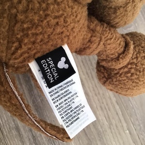 Puede incluir: Peluche marr&oacute;n con una etiqueta que dice "Edici&oacute;n especial" e incluye detalles sobre los materiales utilizados en su construcci&oacute;n. La etiqueta tambi&eacute;n incluye el logotipo de Disney y la siguiente informaci&oacute;n: Hecho en China/Fabrique en Chine/Hecho en China RN 54485/CA 03873 RFC# AEM12060509A EN Body: 88% Polyester Fibers/10% Plastic/1% Polyethylene/1% Polyurethane FR Corps: 88% Fibres de Polyester/10% Plastique /1% Polyethylene/1% Polyurethane