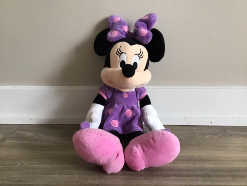 May include: A plush purple and pink Minnie Mouse toy with a purple polka dot dress and pink shoes.