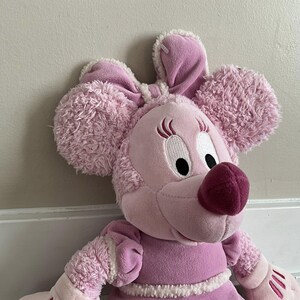 Peut inclure: Une peluche rose en forme de souris avec de grandes oreilles duveteuses et un nez rose fonc&eacute;. Le jouet a des cils brod&eacute;s et une robe rose avec une bordure blanche. La souris est une peluche douce et c&acirc;line.