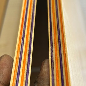 9 Layers of Vibrantly dyed maple veneer ply made with purple and orange colours. Ply sheet measures 45x11x.05 inches. Sheet is polished smooth and finished with a thin layer of poly