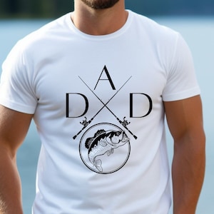 May include: White t-shirt with a black graphic design of two crossed fishing rods and a fish. The design includes the letters "DAD" with the "A" at the top of the crossed rods.