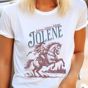 May include: White t-shirt featuring a vintage-style illustration of a woman riding a horse. The text "Jolene Jolene Jolene JOLENE" is printed in blue above the illustration.