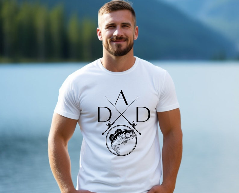May include: White t-shirt with a black graphic design of two crossed fishing rods and a fish. The design includes the letters "DAD" with the "A" at the top of the crossed rods.