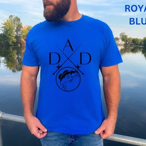 May include: A royal blue t-shirt with a black graphic of two crossed fishing rods and a fish with the letters "A" and "D" on either side of the rods.