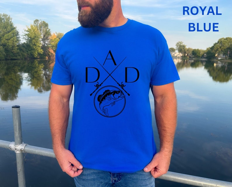 May include: A royal blue t-shirt with a black graphic of two crossed fishing rods and a fish with the letters "A" and "D" on either side of the rods.