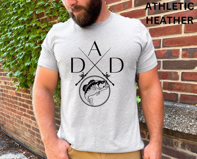 May include: A gray t-shirt with a black graphic of two crossed fishing rods and a bass fish. The text "A D X D" is printed on the shirt.