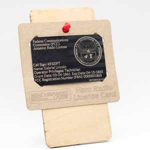 May include: A brown wooden card with the text "Ham Radio License Card" and the text "Federal Communications Commission (FCC) Amateur Radio License" with the call sign KF6DFT, name Gabriel Lincoln, operator privileges Technician, grant date 03-04-1861, expiration date 04-15-1865, and FCC registration number 0000001865.
