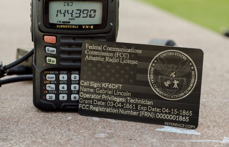 May include: A black and silver metal card with the text "Federal Communications Commission (FCC) Amateur Radio License" and the seal of the United States Federal Communications Commission. The card also includes the call sign KF6DFT, the name Gabriel Lincoln, the operator privileges Technician, the grant date 03-04-1861, the expiration date 04-15-1865, and the FCC registration number (FRN) 0000001865. The card is labeled "Reference Copy".