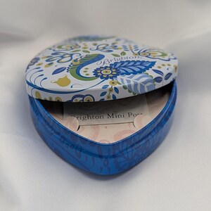 K&ouml;nnte beinhalten: Eine herzf&ouml;rmige Dose mit Klappdeckel, blau und wei&szlig; bemalt mit einem Blumen- und Paisley-Design. Der Deckel ist ge&ouml;ffnet und zeigt das Innere und den Text "Brighton Mini Pouch".