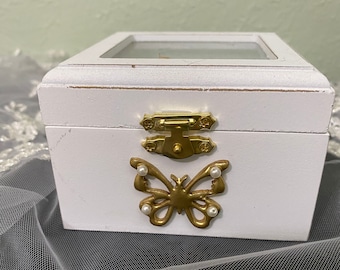 Ring bearer box. White with gold butterfly with pearl accents on wings. Clear top with white satin padded ring holder. Holds two rings.