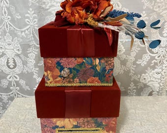 Card Box with Floral Design Two Tiered Enhanced with Burgandy Ribbon and Rows of Beautiful Gold Breaded Trim and Topped with Burgandy Flower
