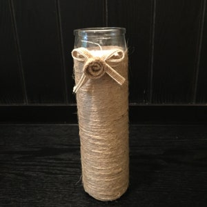 May include: A clear glass cylinder vase wrapped in natural twine with a burlap bow and a small burlap flower.