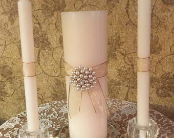 Perfect for any wedding. this ivory pillar candle set is embellished with a shimmering ribbon and a large pearl and rhinestone pendant.