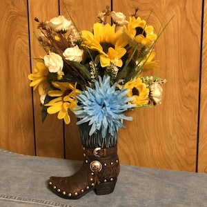 Flower arrangement in brown resin boot with look of tooled leather and turquoise fringe, Sunflower arrangement.  Large quantities available