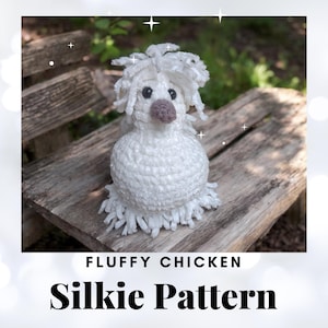 May include: A white crocheted fluffy chicken toy with a grey beak and black eyes. The toy is sitting on a wooden bench. The text "Fluffy Chicken Silkie Pattern" is below the toy.