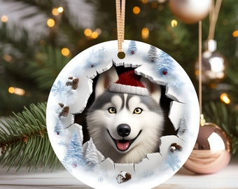 May include: A round white Christmas ornament with a festive winter scene. A husky dog wearing a red Santa hat peeks through a hole in the ornament, surrounded by snowflakes and pine cones.