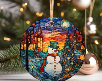 Puede incluir: Adorno navideño redondo con un diseño de vidriera colorido. El adorno presenta un muñeco de nieve con sombrero de copa y bufanda, en un paisaje nevado con un castillo y árboles. El adorno mide unos 7.6 cm de diámetro y tiene una cinta dorada.