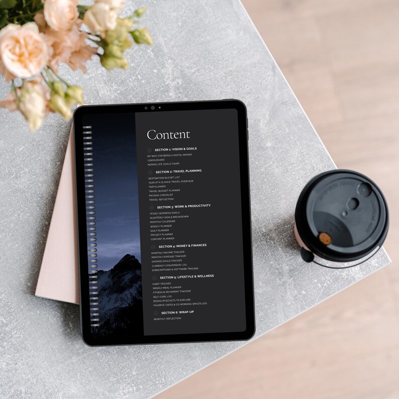 Close-up of a tablet displaying a content outline for a planner on a textured table, with a coffee cup and flowers nearby.
