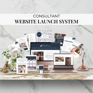 May include: A rose gold laptop, desktop computer, tablet, and smartphone display a website design. The image includes printed documents, a decorative bird, flowers, and a rose gold desk lamp. Text reads "CONSULTANT WEBSITE LAUNCH SYSTEM."