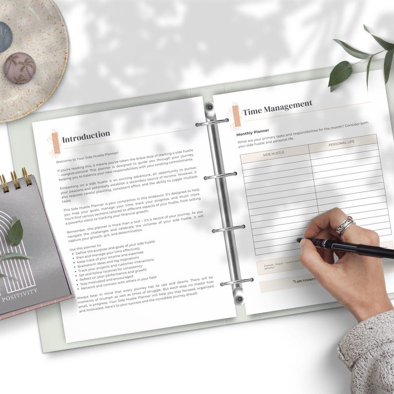 May include: A close-up of a planner with the title "Time Management" and a section for "Monthly Planner". The planner has a section for "Side Hustle" and "Personal Life" with columns for "What are your primary tasks and responsibilities for the month? Consider both your side hustle and personal life."