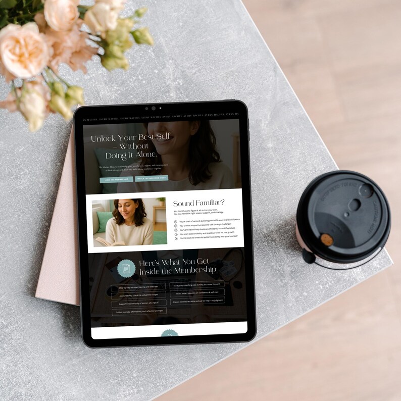 A tablet displaying a wellness or coaching website on a light-colored surface. Nearby, a coffee cup is resting, and a bouquet of flowers is partially visible in the background.