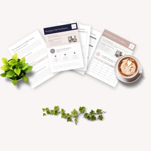 A serene workspace scene featuring several printed worksheets on productivity and organization, a green potted plant, and a cup of latte art coffee, set against a light background.