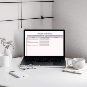 A desk scene featuring a laptop displaying a table titled 'ChatGPT Power Prompts for Marketing Your Business'. A white mug, a notebook, and glasses are on the desk. A small vase with flowers is also present.