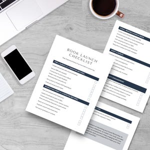 A flat lay of a book launch checklist on a wooden table, featuring sections for pre-launch, marketing, post-launch, and tips, alongside a laptop and a smartphone.