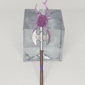 May include: A silver axe with a brown wooden handle and a purple crystal on top. The crystal has a spiky, branch-like design.