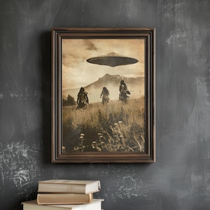May include: Sepia-toned framed print depicting three figures in a field beneath a hovering UFO. The artwork has a vintage aesthetic, with a mountain range in the background. A stack of books rests below the frame.