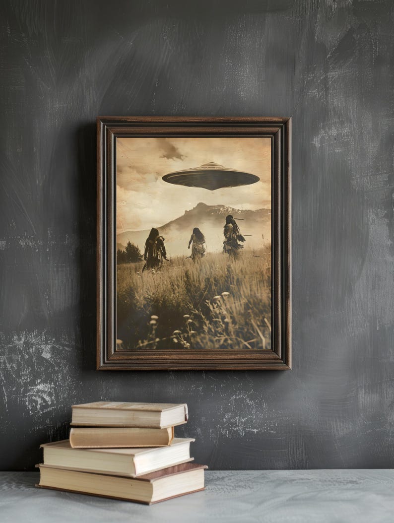 May include: Sepia-toned framed print depicting three figures in a field beneath a hovering UFO. The artwork has a vintage aesthetic, with a mountain range in the background. A stack of books rests below the frame.
