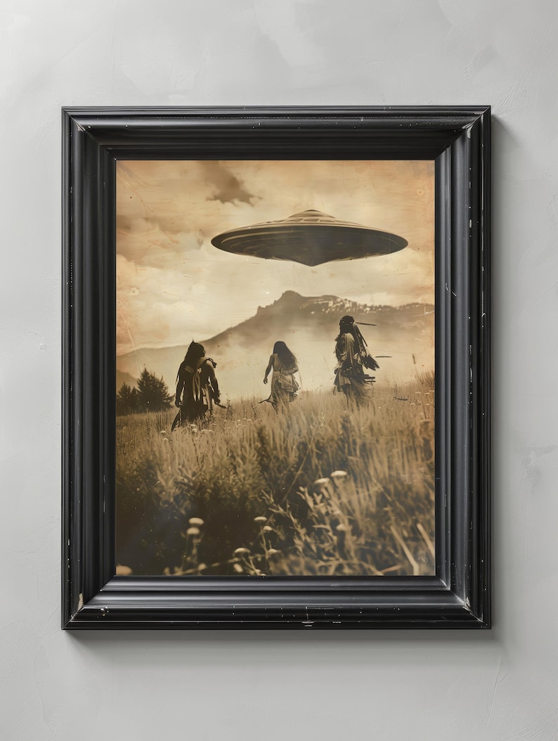May include: Sepia-toned framed print depicting three figures in a field, with a UFO hovering above. The black frame surrounds the image, which features a mountain range in the background and tall grass in the foreground. The artwork evokes a sense of mystery and the unknown.