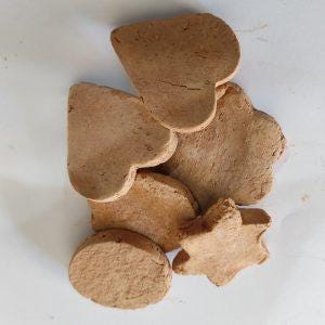Op de afbeelding: Assortiment van bruine klei koekjesvormen in verschillende vormen, waaronder een hart, een ster, een boom, een wolk en een cirkel.