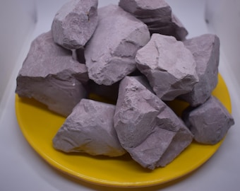 May include: A close-up of a pile of purple clay rocks on a yellow plate. The rocks are irregular in shape and have a rough texture.