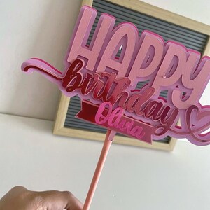 Side view of the pink layered cardstock Happy Birthday cake topper showing paper layers and dimensional depth on a stick.