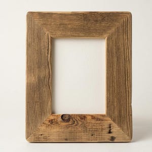 May include: A rectangular picture frame constructed from weathered brown wood with a visible grain pattern and a prominent knot detail at the bottom center. The frame features a simple mitered corner design and surrounds a plain white rectangular center.