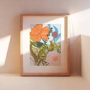 Könnte beinhalten: Ein gerahmter Kunstdruck mit Blumen, der eine lebendige Anordnung von orangefarbenen, rosa und blauen Blumen mit grünem Laub zeigt. Das Kunstwerk ist vor einem hellblauen Hintergrund in einem Naturholzrahmen gerahmt.