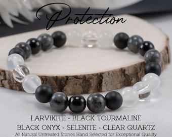 May include: A black, gray, and white beaded bracelet with the words "Protection", "Larvikite - Black Tourmaline", "Black Onyx - Selenite - Clear Quartz", and "All Natural Untreated Stones Hand Selected for Exceptional Quality".