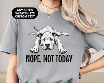 Op de afbeelding: Een grijs t-shirt met korte mouwen en een zwart-witte afbeelding van een hond die plat op de buik ligt. Onder de hond staat de tekst NOPE, NOT TODAY in dikke zwarte hoofdletters. Het shirt heeft een ronde hals en een relaxte pasvorm.