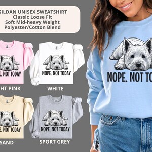 May include: A light blue sweatshirt with a white dog graphic and the text "NOPE. NOT TODAY." The image also shows sweatshirts in light pink, white, sand, and sport grey. The sweatshirts are classic loose fit and made of a polyester/cotton blend.