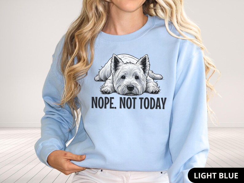 May include: Light blue sweatshirt featuring a graphic of a West Highland White Terrier dog lying down. The text "NOPE. NOT TODAY" is printed below the dog. The sweatshirt is a solid light blue color.